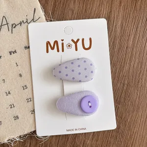 Detail of purple polka dot and button fabric hair clips on white display card