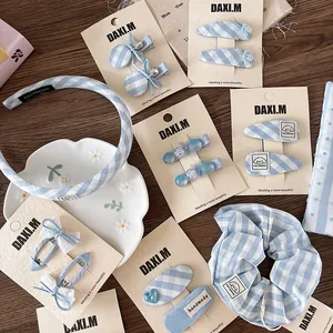 Detailed set of blue and white plaid fabric bows, hair clips and scrunchies on wooden background