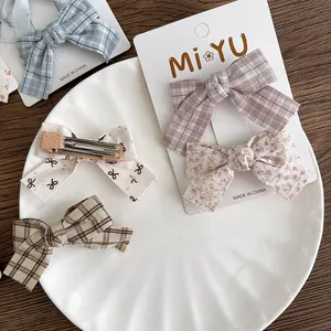Detailed view of floral and plaid fabric bow hair clips with metal duckbill fasteners