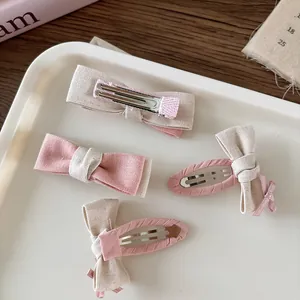 Dettaglio di fermagli per capelli con fiocchi in tessuto rosa e beige in un vassoio decorativo
