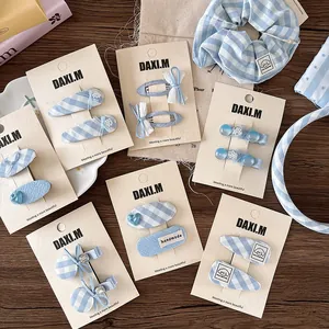 Detailed set of blue plaid bow hair clips, scrunchie and headband on a wooden surface