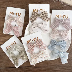 Detail shot of floral and checkered bow hair clips set on a decorative white plate