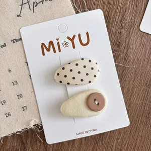 Close-up of fabric hair clips set with polka dots and button detail on card