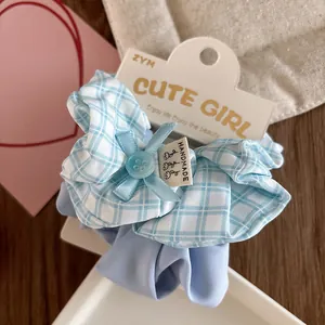 Detail of light blue plaid fabric scrunchie with handmade label and ribbon bow