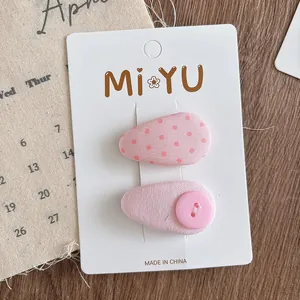 Detail of pink fabric teardrop hair clips with red polka dots and decorative button