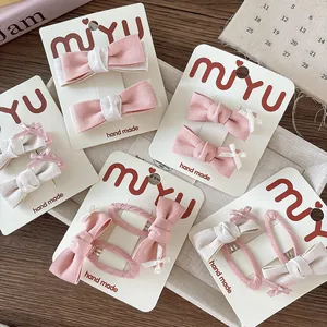 Dettaglio di fermagli per capelli in tessuto rosa e beige fatti a mano su cartoncino