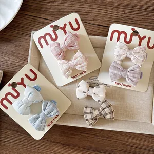 Close-up of handmade floral and plaid fabric bow hair clips for girls in a soft pastel set