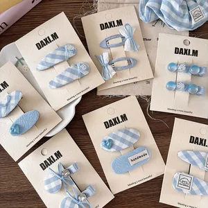Detail of blue plaid fabric hair clips and bow set on card, featuring handmade craftsmanship