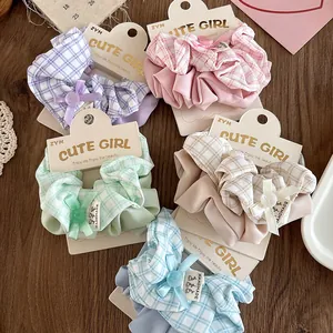 Detail view of five checkered plaid fabric scrunchies with buttons and handmade labels