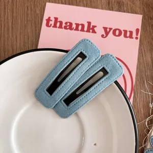 Détail de pinces à cheveux en denim bleu clair avec design rectangulaire creux sur plateau