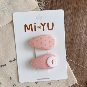 Close-up of pink fabric teardrop hair clips with dots and button on a rustic display