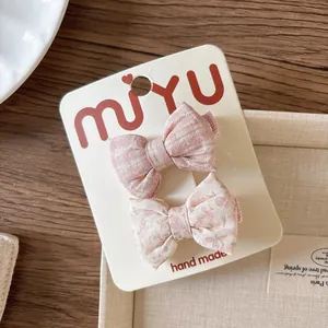 Detail of handmade floral and striped fabric bow hair clips on a branded display card