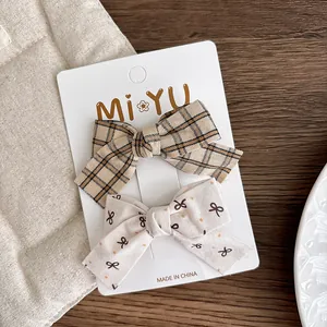 Detail view of khaki plaid and polka dot bow hair clips on a branded card