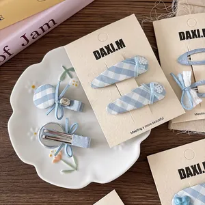 Blue plaid fabric bow hair clips with pearls and heart detail on display card