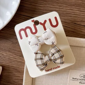 Close-up of a 2-piece set of floral and plaid cotton bow hair clips on a display card