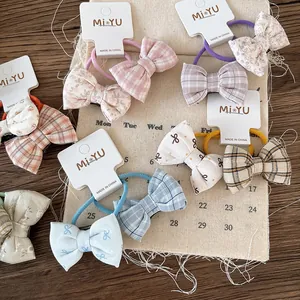 Detail of assorted floral and plaid fabric bow hair ties set for girls on rustic linen