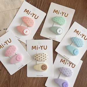 Close-up of fabric drop-shaped hair clips with polka dots and buttons in various pastel colors