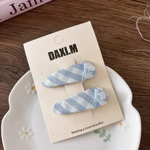 Close-up of blue plaid bow hair clips with white pearls on a display card holder