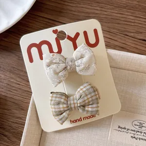 Detail of floral and plaid fabric bow hair clips displayed on branded packaging card