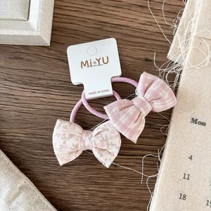 Close-up of pink plaid and floral fabric bow hair ties set on dark wooden surface