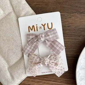 Detail view of plaid and floral fabric bow hair clips on a white display card