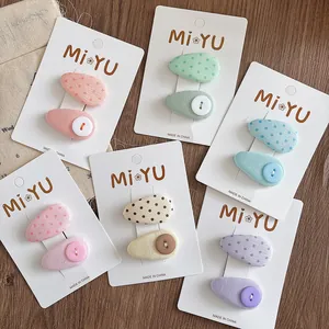 Detailed set of colorful fabric drop hair clips with polka dots and buttons on a card
