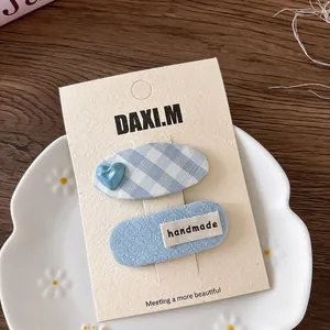 Detailed view of blue plaid bow hair clips and handmade tags in a ceramic dish