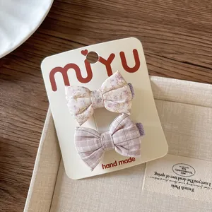 Detail of handmade floral and plaid bow hair clips on a premium white display card