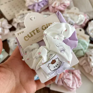 Close-up of white fabric scrunchie with pink floral and rabbit patterns on display card