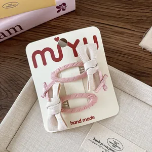 Dettaglio di fermagli per capelli con fiocchi in tessuto rosa e beige fatti a mano per bimba