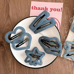 Détail de barrettes à cheveux en denim bleu, formes cœur et étoile sur un plateau décoré
