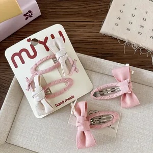Dettaglio di fermagli per capelli con fiocco in tessuto rosa e beige fatti a mano