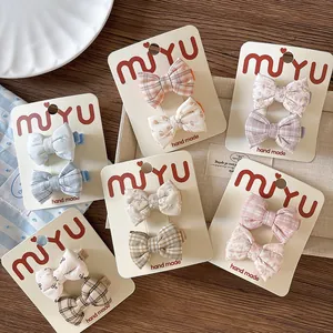 Detail of six sets of handmade cotton bow hair clips with floral and plaid fabric patterns