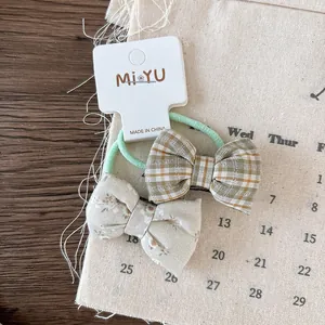Detail of plaid green bow and floral fabric hair ties on minimalist display card