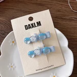 Detail of blue plaid bow hair clips with pearls on display card over ceramic plate