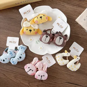 Detail of plush animal hair ties featuring cute 3D embroidery on a white ceramic plate