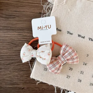 Detail of floral and orange plaid fabric bow hair ties on a display card for girls