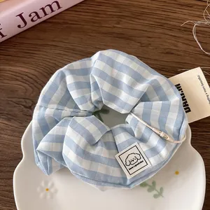 Blue and white checkered hair scrunchie with cute cartoon label on a floral ceramic tray