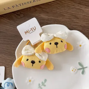 Close-up of two cute yellow cartoon dog hair ties with embroidery and white bows