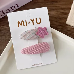 Detail of sweet pink plaid hair clips with glitter star and woven texture on display card