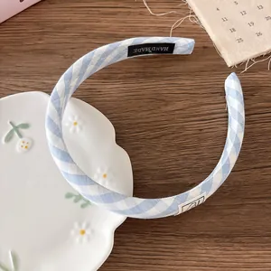 Detail view of handmade light blue checkered fabric headband on rustic wood background