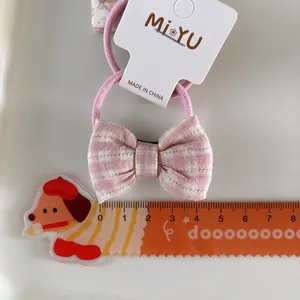 Detailed view of a pink plaid bow hair tie with high-elastic rubber band and ruler