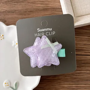 Détail d'une pince à cheveux étoile à paillettes mauves avec dentelle et ruban