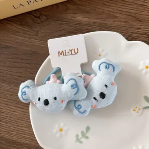 Detail of plush koala hair ties with blue linen texture and fine animal embroidery