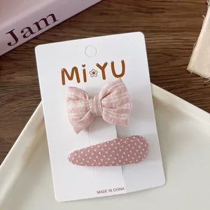 Detail of pink fabric bow hair clips and polka dot clip on a white display card