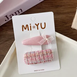 Detail of sweet pink fabric bow hairpins and tweed clip on a display card for girls
