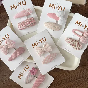 Detailed close-up of pink fabric bow hair clips and floral star hairpins on display cards