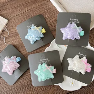 Détail de cinq barrettes étoiles pailletées aux couleurs pastel sur une carte de support