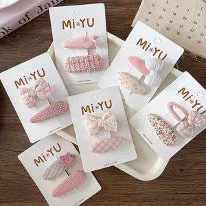 Close-up of pink floral and checkered fabric bow hair clips for girls set on card