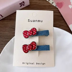 Detailed view of red polka dot bow hair clips wrapped in blue denim fabric on card